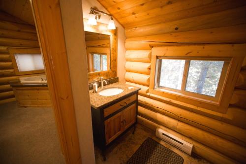 baño con lavabo y espejo en una cabaña de madera en The Pines at Island Park, en Island Park