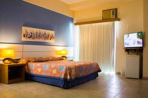 a bedroom with a bed and a flat screen tv at Pousada Barlavento in Iriri