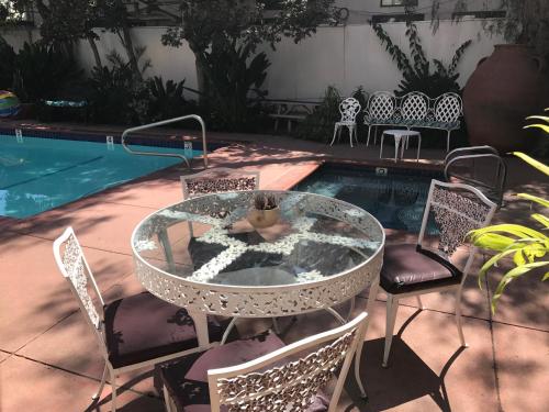 a glass table and chairs next to a swimming pool at Villa Rosa Inn in Santa Barbara