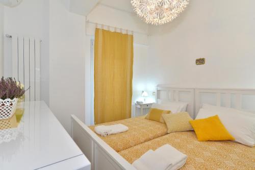 a white bedroom with a bed with yellow pillows at Fidanza House in Bagnoregio