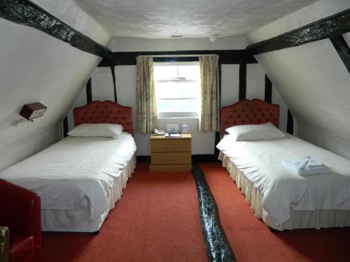 a bedroom with two beds and a window at The Cedars Hotel in Stowmarket
