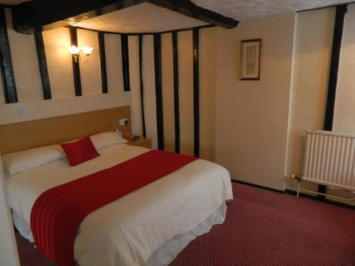 a bedroom with a bed with a red and white blanket at The Cedars Hotel in Stowmarket