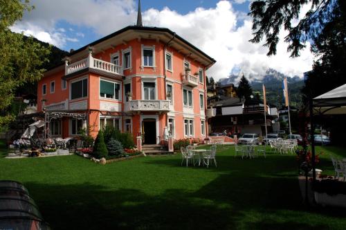 a large house with tables and chairs in a yard at Hotel Luis in Fiera di Primiero