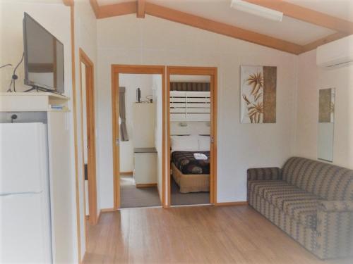 a living room with a couch and a television at Golden Country Motel and Caravan Park in Maryborough