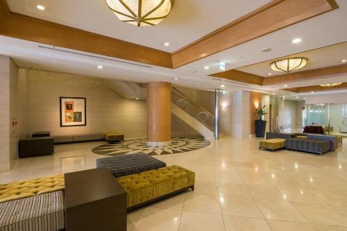 a lobby with couches and a staircase in a building at HOTEL MYSTAYS Matsuyama in Matsuyama