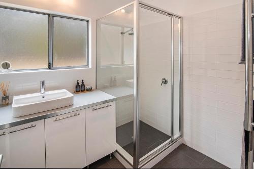 een witte badkamer met een wastafel en een douche bij Margaret River Farmhouse in Rosa Glen