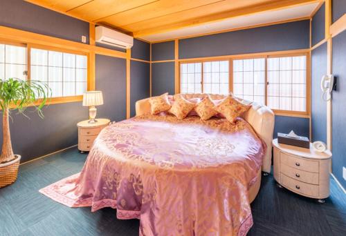 a bedroom with a large bed in a room with windows at Hanaingen in Kusatsu