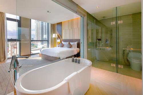 een grote badkamer met een bad en een bed en een bad bij New Orient Hotel Da Nang in Da Nang