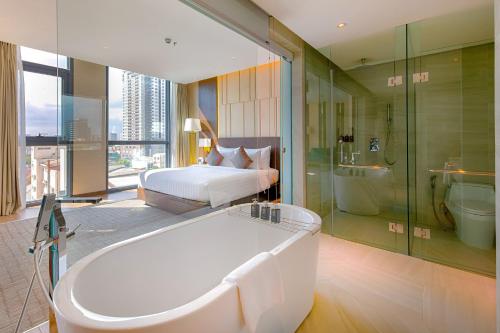 a large bathroom with a tub and a bed and a tub at New Orient Hotel Da Nang in Danang