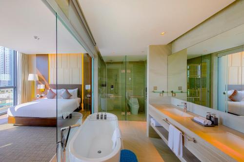 a bathroom with a bed and a bath tub and a bed at New Orient Hotel Da Nang in Da Nang