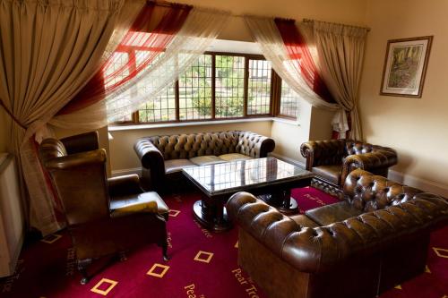 a living room with leather couches and a table at The Pear Tree Inn & Country Hotel in Worcester