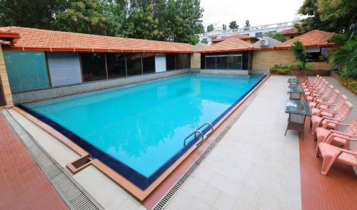 a large swimming pool with chairs around it at Jal Mahal Resort and Spa in Mysore