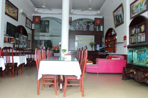 een eetkamer met een tafel en stoelen en een roze bank bij Xuan Hoa Hotel in Ninh Binh