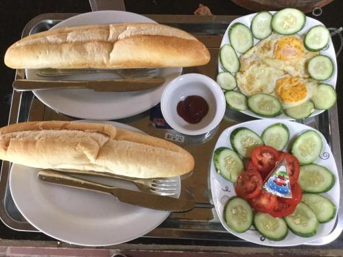 a table with plates of food with a sandwich and a salad at Xuan Hoa Hotel in Ninh Binh