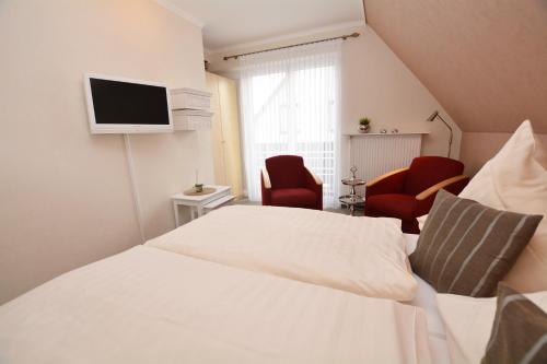 a bedroom with a bed and a tv on a wall at Hotel-Pension Anjo in Büsum