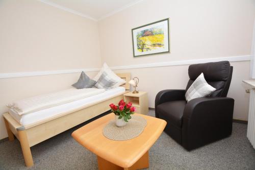 a living room with a couch and a chair and a table at Hotel-Pension Anjo in Büsum
