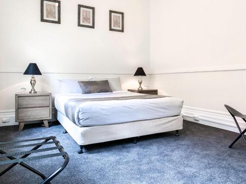 a bedroom with a bed and two tables and a chair at Waratah On York in Launceston
