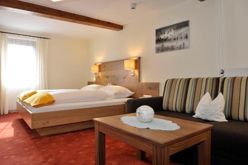 une chambre d'hôtel avec un lit et un canapé dans l'établissement Gasthof Tetter, à Schladming