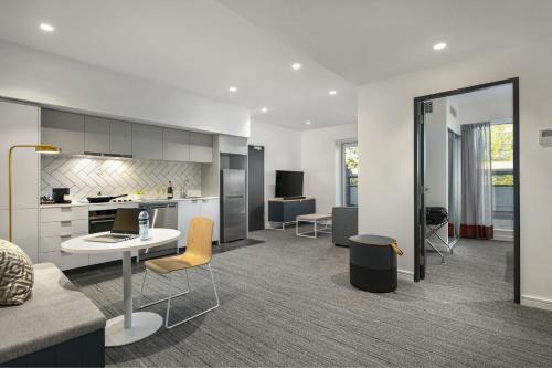 an open kitchen and living room with a table and chairs at Quest Canberra City Walk in Canberra
