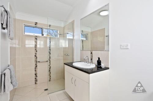 a white bathroom with a sink and a shower at Pelican Rest Tourist Park in Saint George