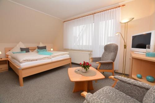 a hotel room with a bed and a chair and a table at Hotel-Pension Anjo in Büsum