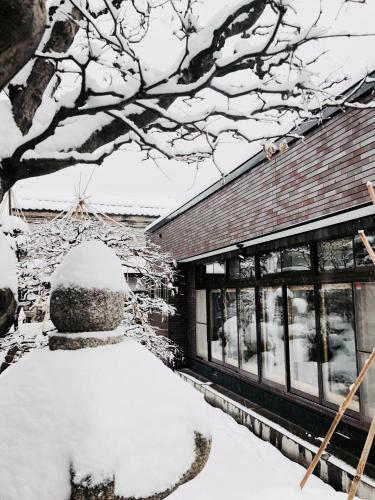 a yard covered in snow next to a building at Otarunishikien in Otaru