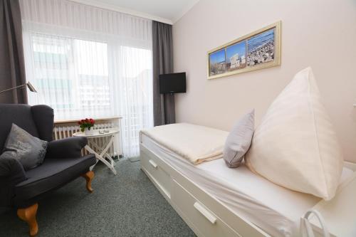 a bedroom with a bed and a chair and a window at Hotel-Pension Anjo in Büsum