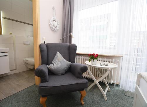 a living room with a chair and a table at Hotel-Pension Anjo in Büsum