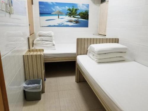 a room with two beds and a picture of a beach at Asia Travel House in Hong Kong