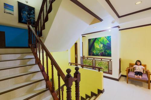 a staircase in a house with a woman sitting in a chair at Grand Orchid Inn Patong beach in Patong Beach