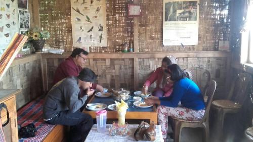 um grupo de pessoas sentadas à mesa a comer em Vamoose Red Panda em Sombāri
