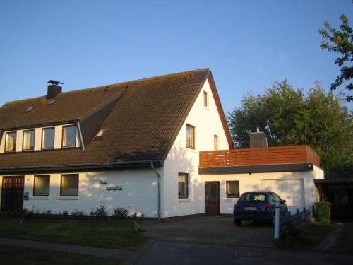 una casa blanca con un coche aparcado delante de ella en Haus-Halligblick-Ferienwohnung-Groede, en Dagebüll