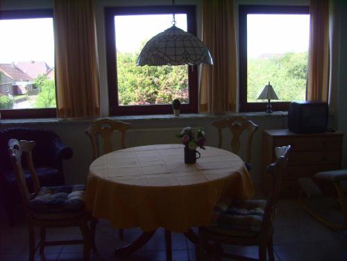 ein Esszimmer mit einem Tisch, Stühlen und Fenstern in der Unterkunft Haus Halligblick, Ferienwohnung Hamburger Hallig in Dagebüll