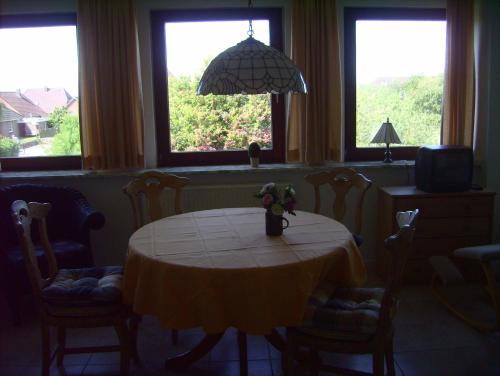 - une salle à manger avec une table, des chaises et des fenêtres dans l'établissement Haus-Halligblick-Ferienwohnung-Hamburger-Hallig, à Dagebüll