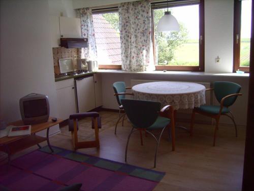 y cocina con mesa, sillas y mesa pequeña. en Haus-Halligblick-Ferienwohnung-Groede, en Dagebüll