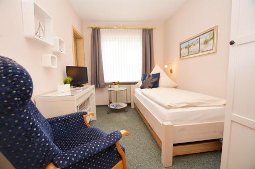 a small room with a bed and a chair at Hotel-Pension Anjo in Büsum