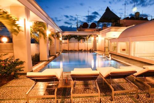 une piscine avec des chaises longues et une maison dans l'établissement Rembrandt Hotel Nha Trang, à Nha Trang