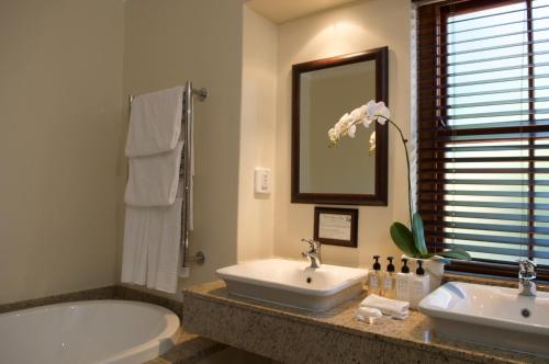 łazienka z 2 umywalkami, wanną i lustrem w obiekcie Glen Avon Lodge Boutique Hotel w Kapsztadzie