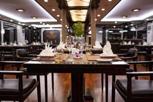 下龙湾Peony Cruises的用餐室配有带玻璃杯和餐巾的长桌