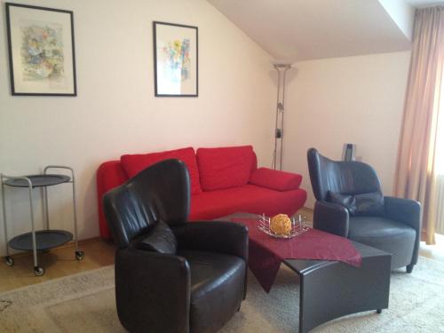 a living room with a red couch and two chairs at Ferienresidenz Am weißen Regen in Bad Koetzting