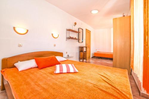 a bedroom with a bed with an orange blanket at Apartments Salčinović in Medulin