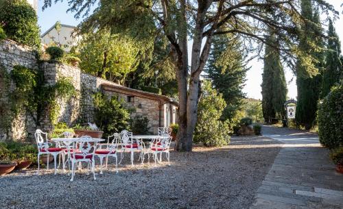 a patio with tables and chairs in a garden at Relais Vignale & Spa in Radda in Chianti