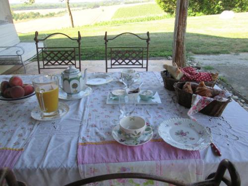 un tavolo con cibo e tazze e piatti sopra di Chambres d'Hôtes Le Loubet a LʼIsle-Jourdain