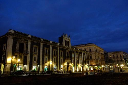 a large building with a clock tower at night at Domoikos in Catania