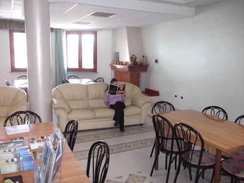 a woman sitting on a couch reading a book at Hotel Meridiana in Arbus
