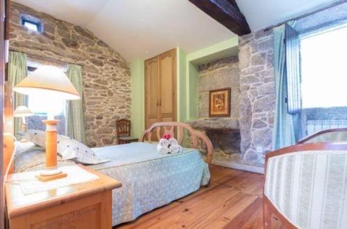 a bedroom with a bed and a stone wall at Casa Da Urcela in Ponteareas