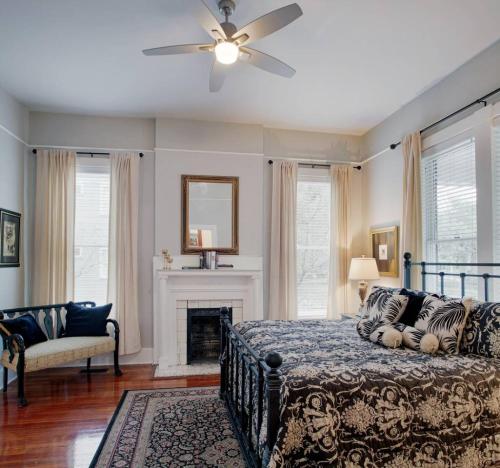 a bedroom with a bed with a ceiling fan and a fireplace at 420Waldburg A · Modern Apt with Southern Charm Blocks from Forsyth in Savannah