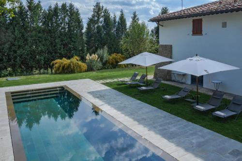 a pool with chairs and umbrellas next to a house at Viesca Toscana Suites & Villas in Reggello