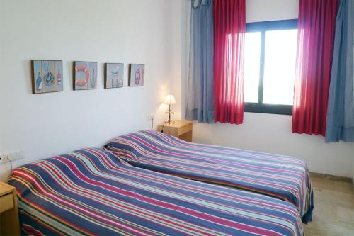 een bed met een gestreepte deken in een slaapkamer bij Marina Real 112 in Manilva