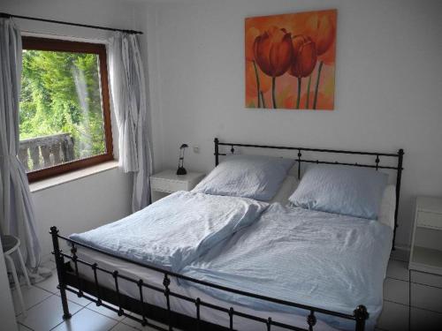 1 cama en un dormitorio con ventana y una foto en Haus Seeromantik, en Uhldingen-Mühlhofen